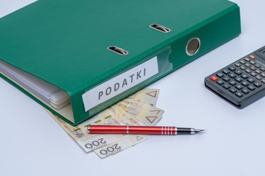 Zielony segregator opisany "PODATKI" leży na biurku w biurze rachunkowym.